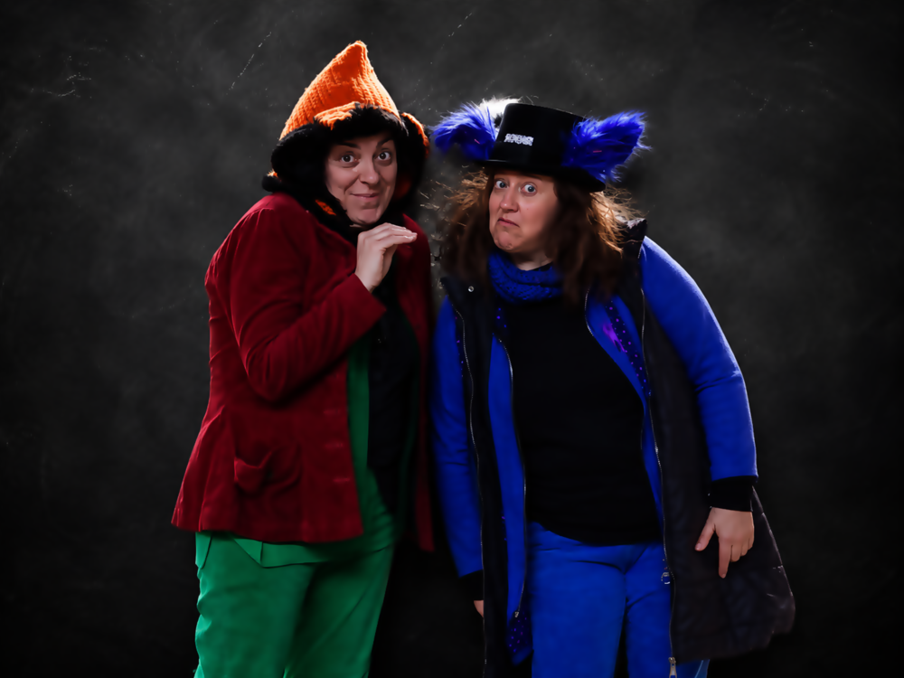 Dos cuentacuentos en Asturias: Verde (izq, sombrero naranja de raposa) y Azul (der, sombrero de copa con orejas de lobo peludas azules grandes), de 'VA de Verde y Azul', posando en un estudio.